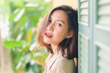 Kadınlar eski ahşap pencerelerle duvara karşı duruyorlar..