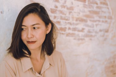 Kadınlar eski beyaz tuğla duvarlara karşı duruyor.