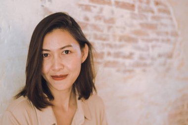 Kadınlar eski beyaz tuğla duvarlara karşı duruyor.