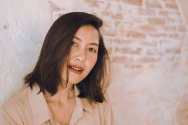 Kadınlar eski beyaz tuğla duvarlara karşı duruyor.