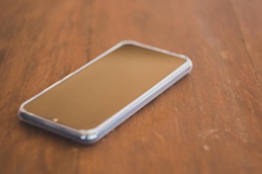 Siyah akıllı telefonlar kahverengi ahşap bir masaya yerleştirilir