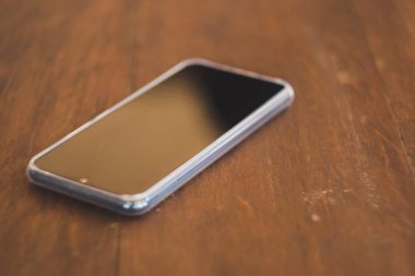 Siyah akıllı telefonlar kahverengi ahşap bir masaya yerleştirilir