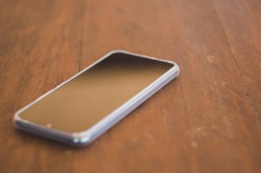 Siyah akıllı telefonlar kahverengi ahşap bir masaya yerleştirilir