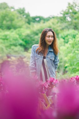 Pembe çiçek bahçesinde duran bir kadın.