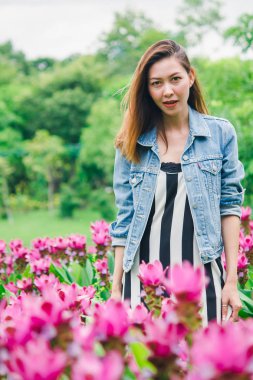 Pembe çiçek bahçesinde duran bir kadın.