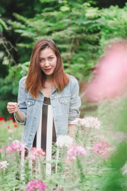 Pembe çiçek bahçesinde duran bir kadın.