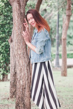 Parkta ağaca yaslanmış bir kadın.