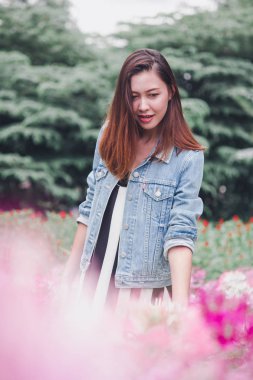 Pembe çiçek bahçesinde duran bir kadın.