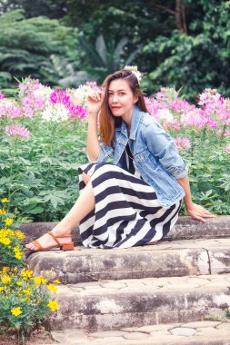 Çiçeklerin güzel çiçek açtığı bir parkta oturan kadın.