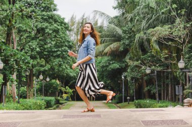 Uzun etek giyen bir kadın yerden atlıyor.