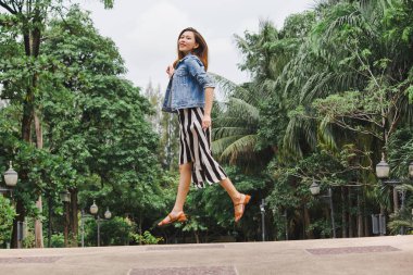 Uzun etek giyen bir kadın yerden atlıyor.