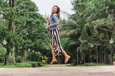 Uzun etek giyen bir kadın yerden atlıyor.