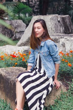 Çiçeklerin güzel çiçek açtığı bir parkta oturan kadın.