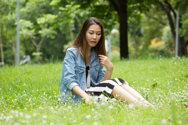 一个长发的女人坐在草坪上 — 图库照片