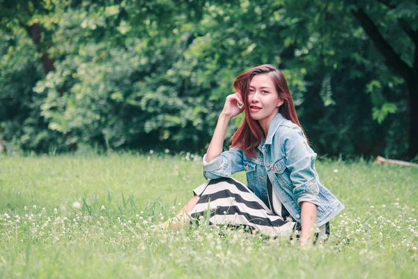 一个长发的女人坐在草坪上 — 图库照片
