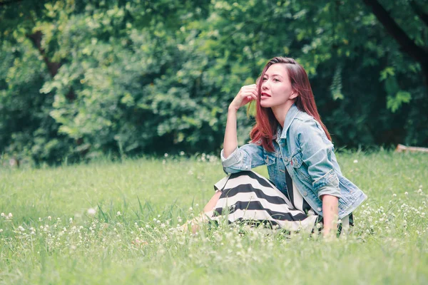 一个长发的女人坐在草坪上 — 图库照片