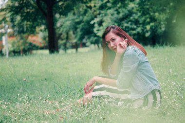 Çimenlerde oturan uzun saçlı bir kadın
