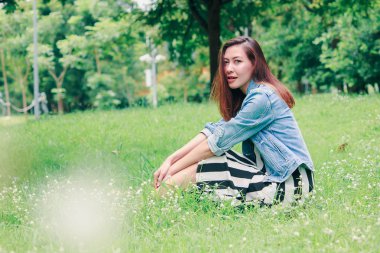 Çimenlerde oturan uzun saçlı bir kadın