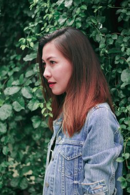 Ağaç duvarın karşısında duran uzun saçlı bir kadın