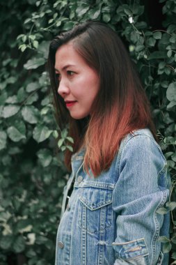 Ağaç duvarın karşısında duran uzun saçlı bir kadın