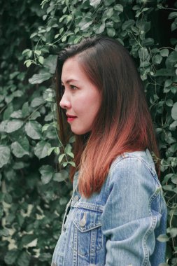 Ağaç duvarın karşısında duran uzun saçlı bir kadın