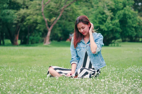 一个长发的女人坐在草坪上 — 图库照片