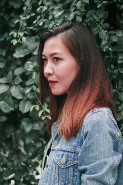 Ağaç duvarın karşısında duran uzun saçlı bir kadın