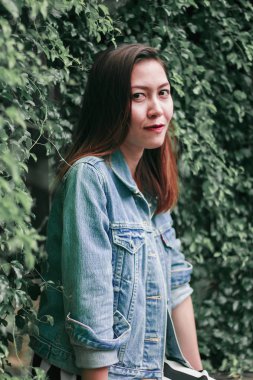 Ağaç duvarın karşısında duran uzun saçlı bir kadın