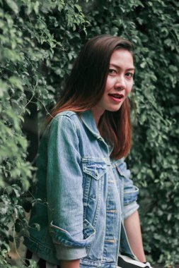 Ağaç duvarın karşısında duran uzun saçlı bir kadın