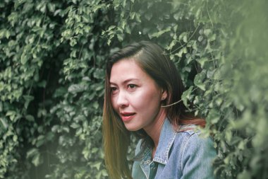 Ağaç duvarın karşısında duran uzun saçlı bir kadın