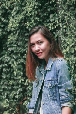 Ağaç duvarın karşısında duran uzun saçlı bir kadın