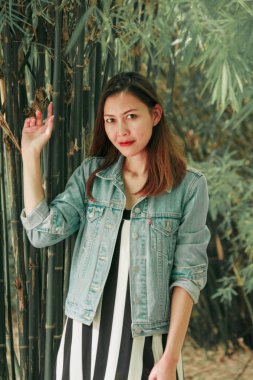 parkta bir bambu ağacının altında duran kadın