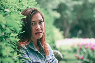 Ağaç duvarın karşısında duran uzun saçlı bir kadın