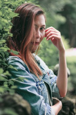 Ağaç duvarın karşısında duran uzun saçlı bir kadın