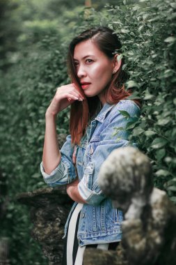 Ağaç duvarın karşısında duran uzun saçlı bir kadın