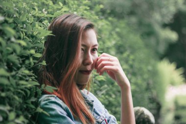 Ağaç duvarın karşısında duran uzun saçlı bir kadın