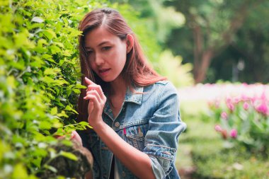 Ağaç duvarın karşısında duran uzun saçlı bir kadın