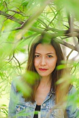 Bir ağacın altında duran uzun saçlı bir kadın