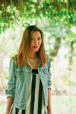 Bir ağacın altında duran uzun saçlı bir kadın