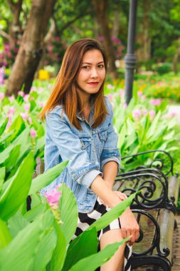 Parkta çiçek bahçesinde oturan kadın