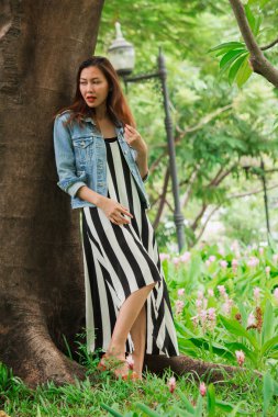 Parkta ağaca yaslanmış bir kadın.