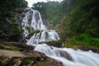 Doğal bir şelale uçurumdan akan bir vadiye doğru uzun bir hat çizer..