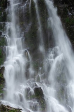 Doğal bir şelale uçurumdan akan bir vadiye doğru uzun bir hat çizer..