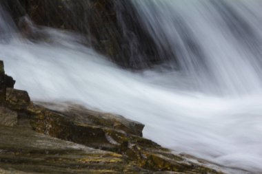 Doğal bir şelale uçurumdan akan bir vadiye doğru uzun bir hat çizer..