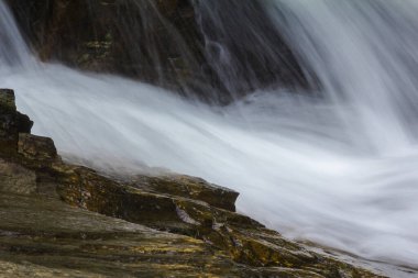 Doğal bir şelale uçurumdan akan bir vadiye doğru uzun bir hat çizer..