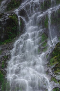 Doğal bir şelale uçurumdan akan bir vadiye doğru uzun bir hat çizer..