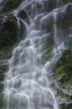 Doğal bir şelale uçurumdan akan bir vadiye doğru uzun bir hat çizer..