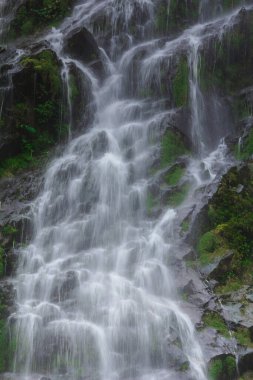 Doğal bir şelale uçurumdan akan bir vadiye doğru uzun bir hat çizer..