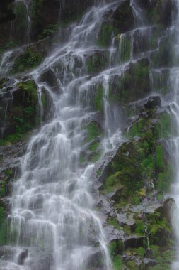 Doğal bir şelale uçurumdan akan bir vadiye doğru uzun bir hat çizer..