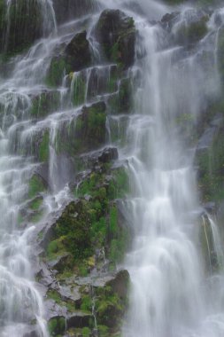 Doğal bir şelale uçurumdan akan bir vadiye doğru uzun bir hat çizer..